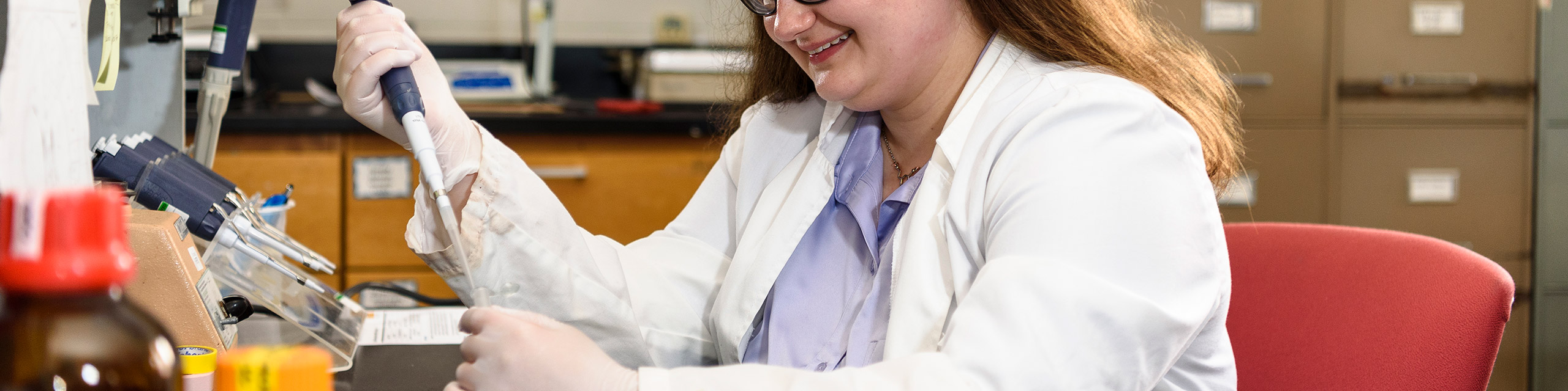 A student wearing a lab coat working on a research